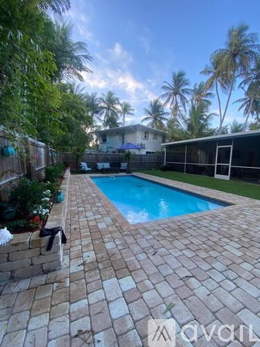 A pool surrounded by a brick patio and a wooden fence.