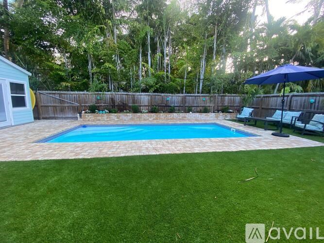A small pool surrounded by a wooden fence and a green lawn.