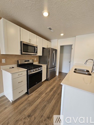 A kitchen with white cabinets and a wooden floor.