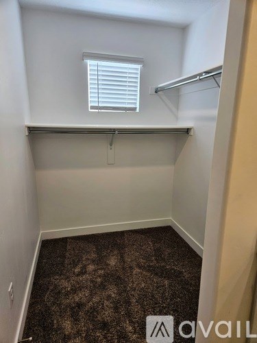A small, empty room with a carpeted floor and a window with blinds.