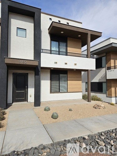 A modern two-story house with a balcony on the second floor.