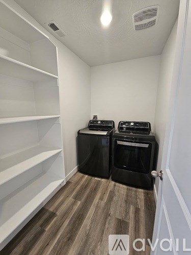 A kitchen pantry with two black ovens and white shelves.