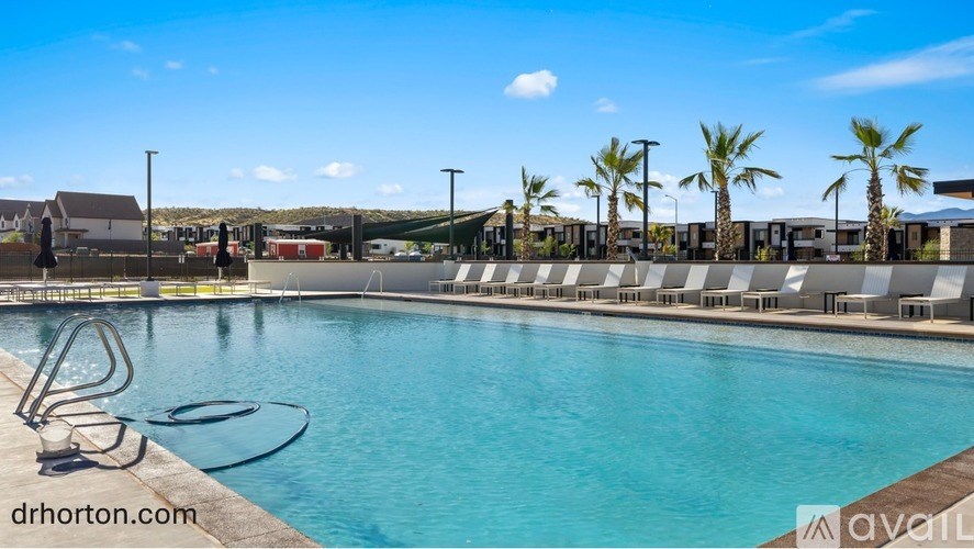 A swimming pool with sun loungers and palm trees in the background.