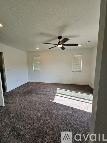 A room with a ceiling fan and carpeted floor.