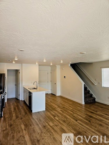 A spacious kitchen with wooden floors and a staircase in the background.