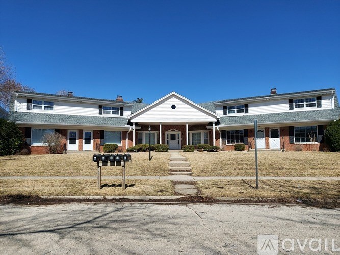 A two-story house with a front porch and a mailbox on the lawn.