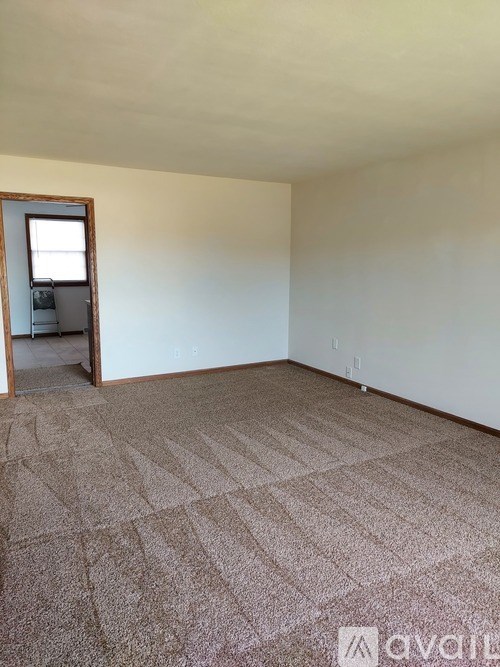 A room with a carpeted floor and a doorway leading to another room.