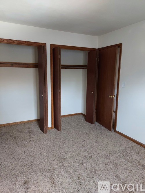 A room with a carpeted floor and two open doors.