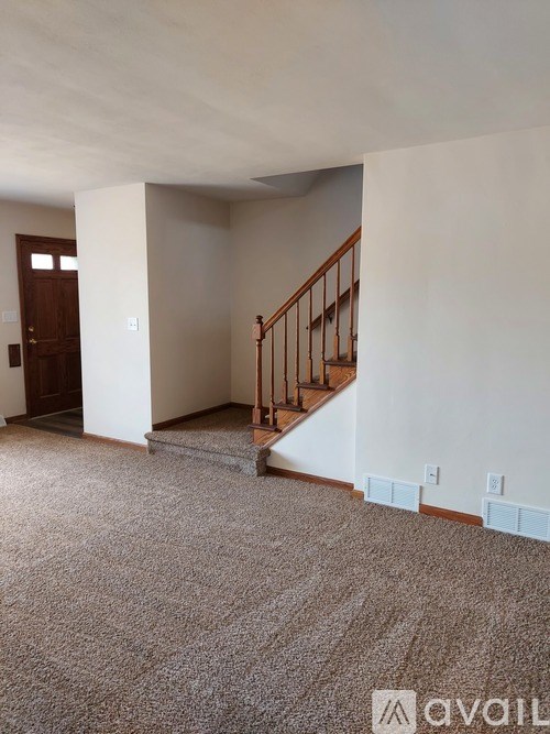 A carpeted room with a staircase leading to another room.