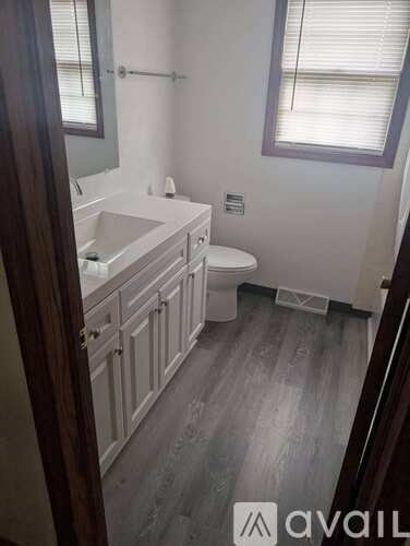 A bathroom with a toilet, sink, and mirror.
