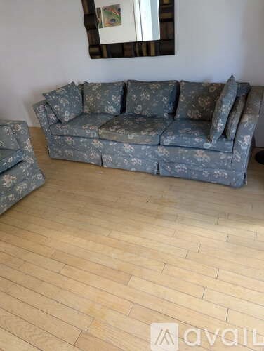 A grey floral patterned sofa with a matching armchair in a room with wooden flooring.