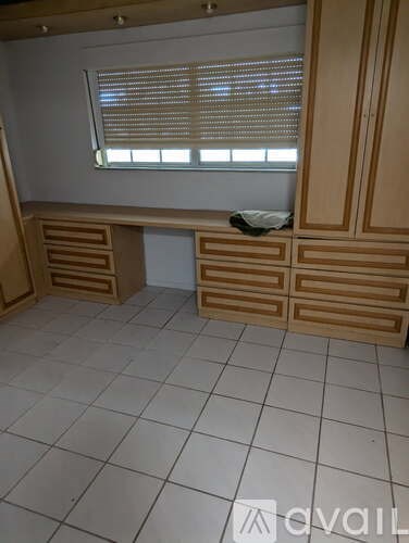 A room with wooden cabinets and a window with blinds.