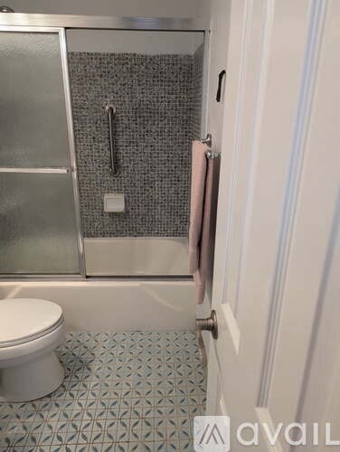A bathroom with a toilet, a shower with a glass door, and a tiled floor.