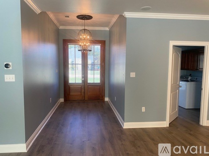 A room with a wooden floor and a chandelier hanging from the ceiling.