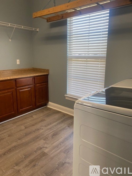 A room with a white washing machine and a wooden cabinet.