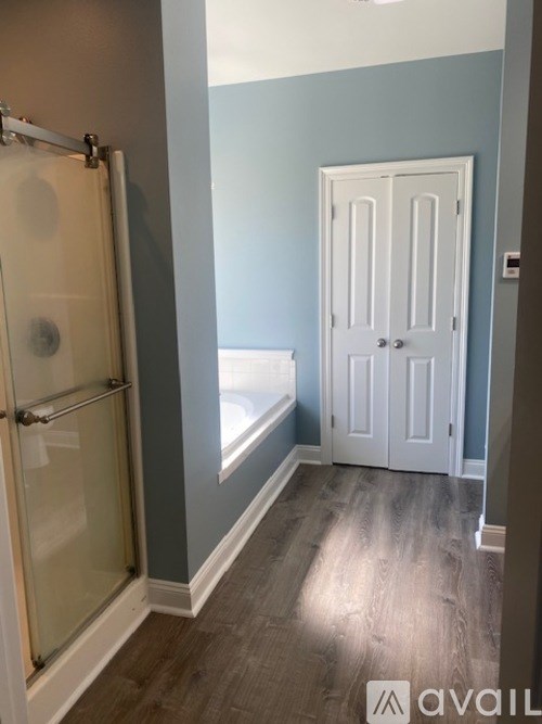 A bathroom with a glass shower door and a white door.