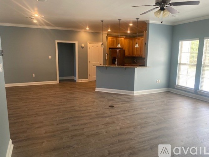 A spacious room with wooden flooring and a ceiling fan.