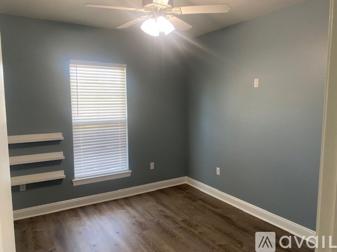 A room with a ceiling fan and a window with blinds.