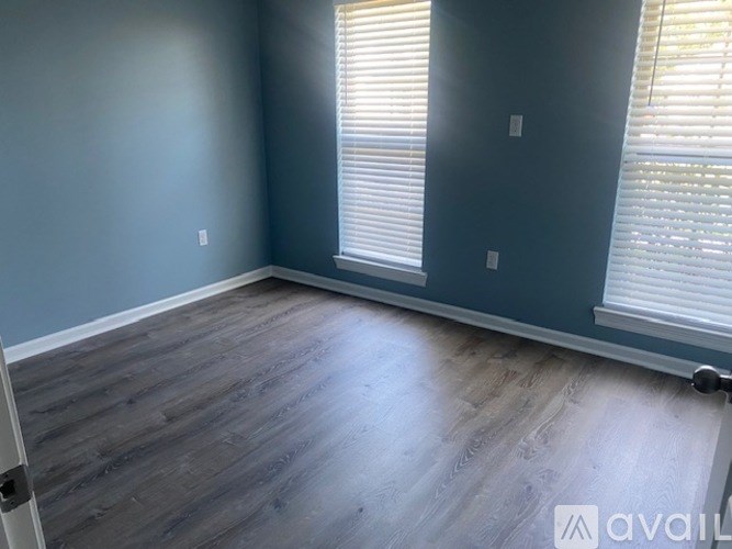 A room with wooden flooring and a window with blinds.