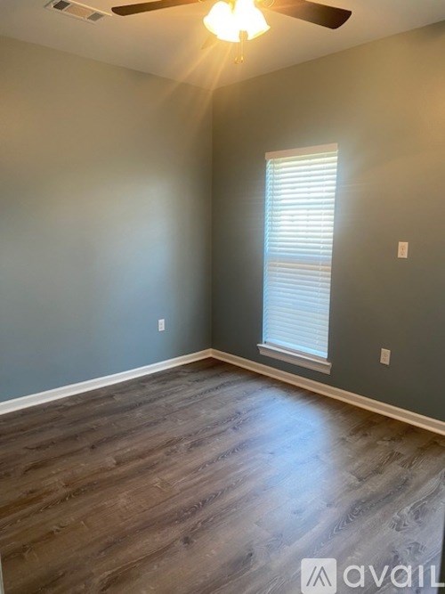 A room with a ceiling fan and a window with blinds.