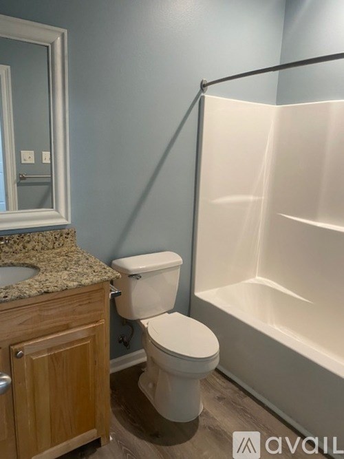 A bathroom with a toilet, a bathtub, and a mirror.