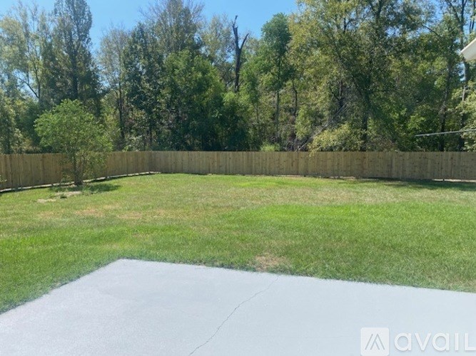 A backyard with a concrete slab and a wooden fence.