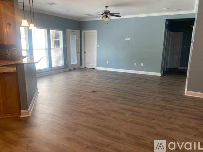 A spacious room with wooden flooring and a ceiling fan.