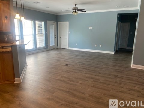 A spacious room with wooden flooring and a ceiling fan.