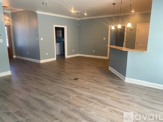 A spacious room with wooden flooring and a mirror on the wall.