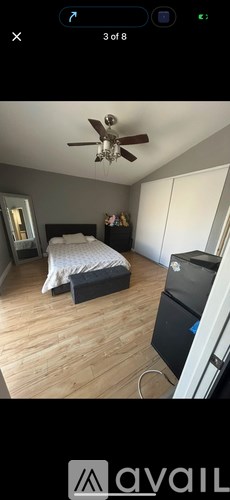 A room with a bed, a ceiling fan, and a cabinet.