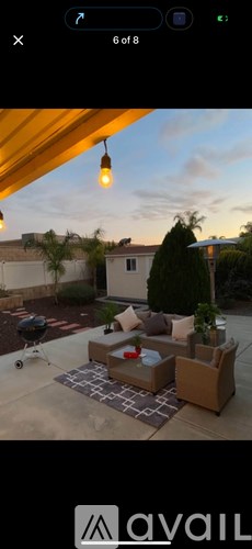 A patio with a couch, a coffee table, and a lamp.
