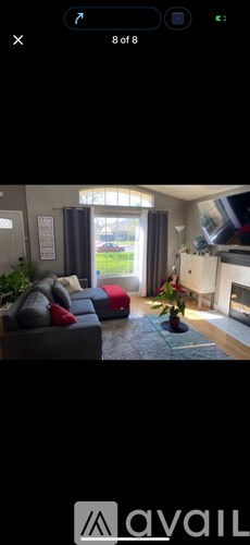 A living room with a grey couch and a red pillow.