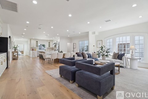 A spacious living room with a grey sofa set and wooden flooring.