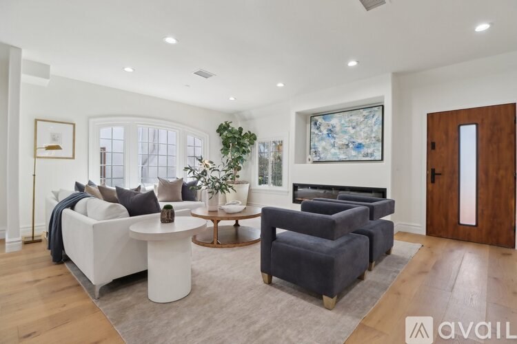 A living room with a white sofa, a grey armchair, a wooden coffee table, and a painting on the wall.