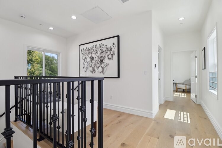 A black railing on a wooden floor in a white room.