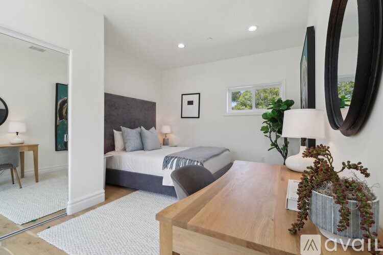 A bedroom with a bed, a table, and a mirror.