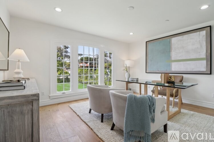 A modern living room with a glass table and a large painting on the wall.