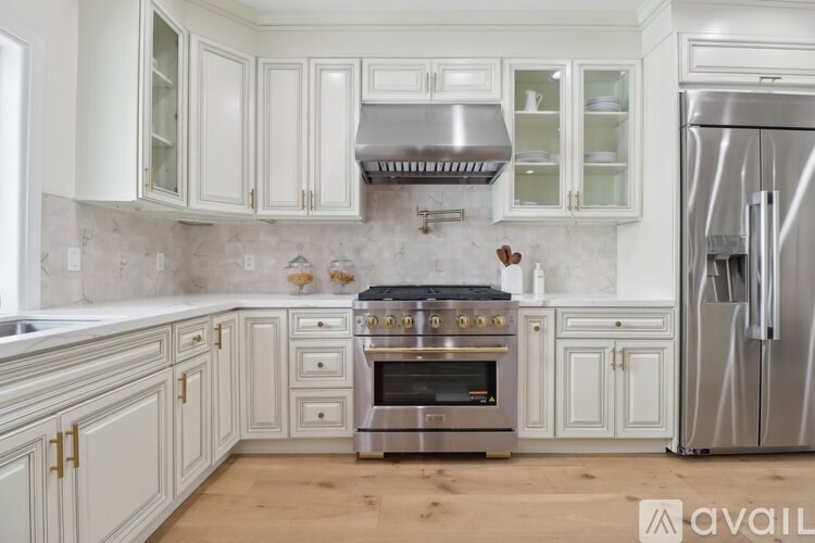 A modern kitchen with white cabinets and a stainless steel refrigerator.