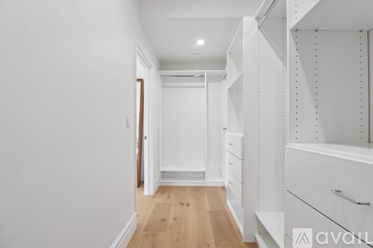 A long hallway with white walls and wood floors.