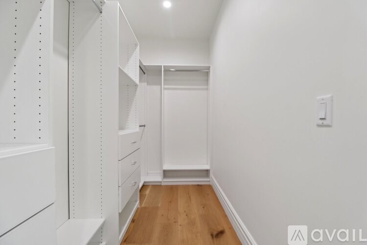 A long hallway with white walls and wood floors.