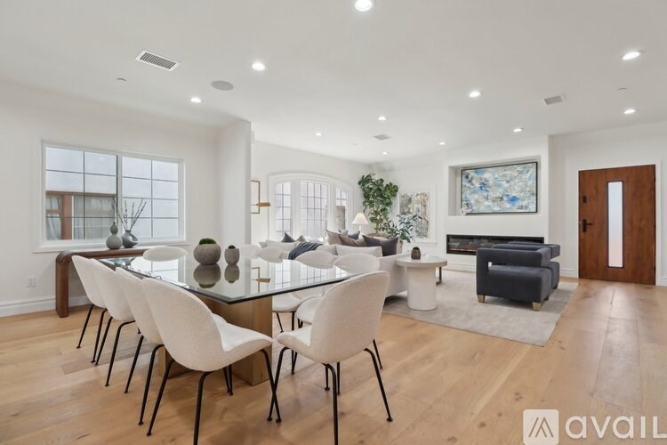 A modern dining room with a glass table and white chairs.