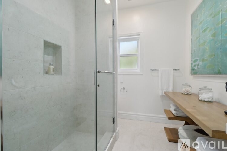 A bathroom with a glass shower stall and a wooden table.