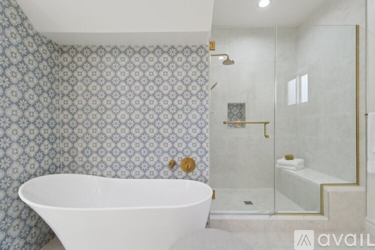 A white bathtub sits in a bathroom with a patterned wallpaper.