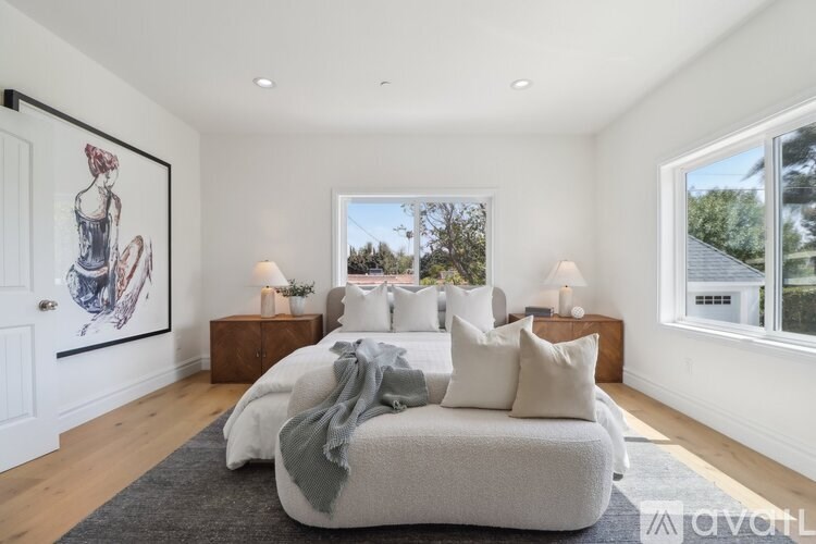 A bedroom with a large bed and a framed picture on the wall.