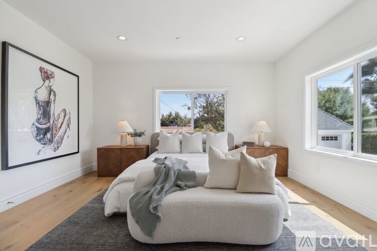A bedroom with a large bed and a framed picture on the wall.
