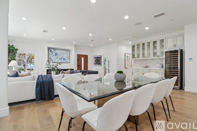 A modern dining room with a glass table and white chairs.