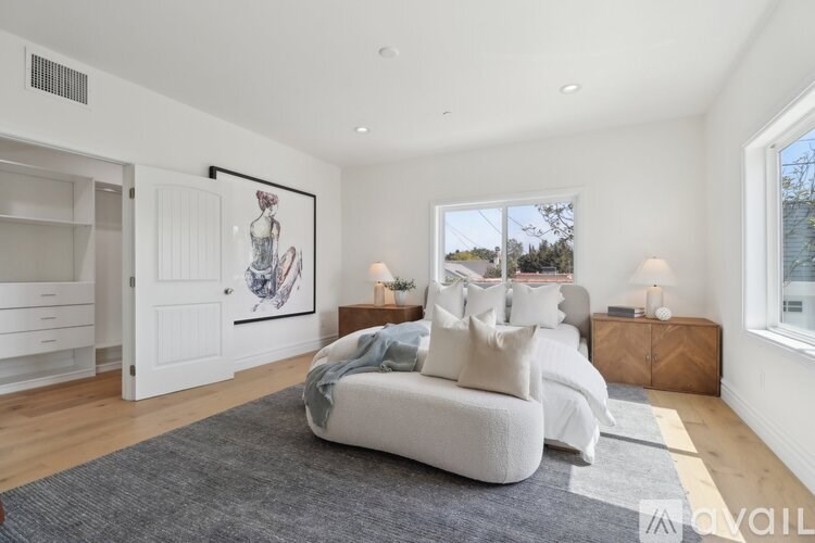 A bedroom with a large bed and a painting on the wall.