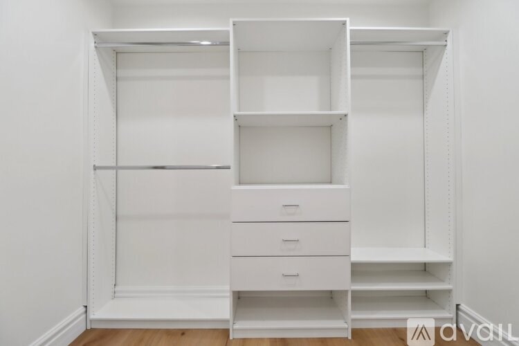 A white shelving unit with drawers is in a room with white walls.