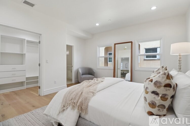 A bedroom with a large bed and a grey chair.