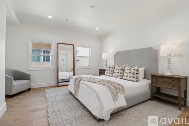 A bedroom with a large bed, a grey headboard, and a wooden nightstand.